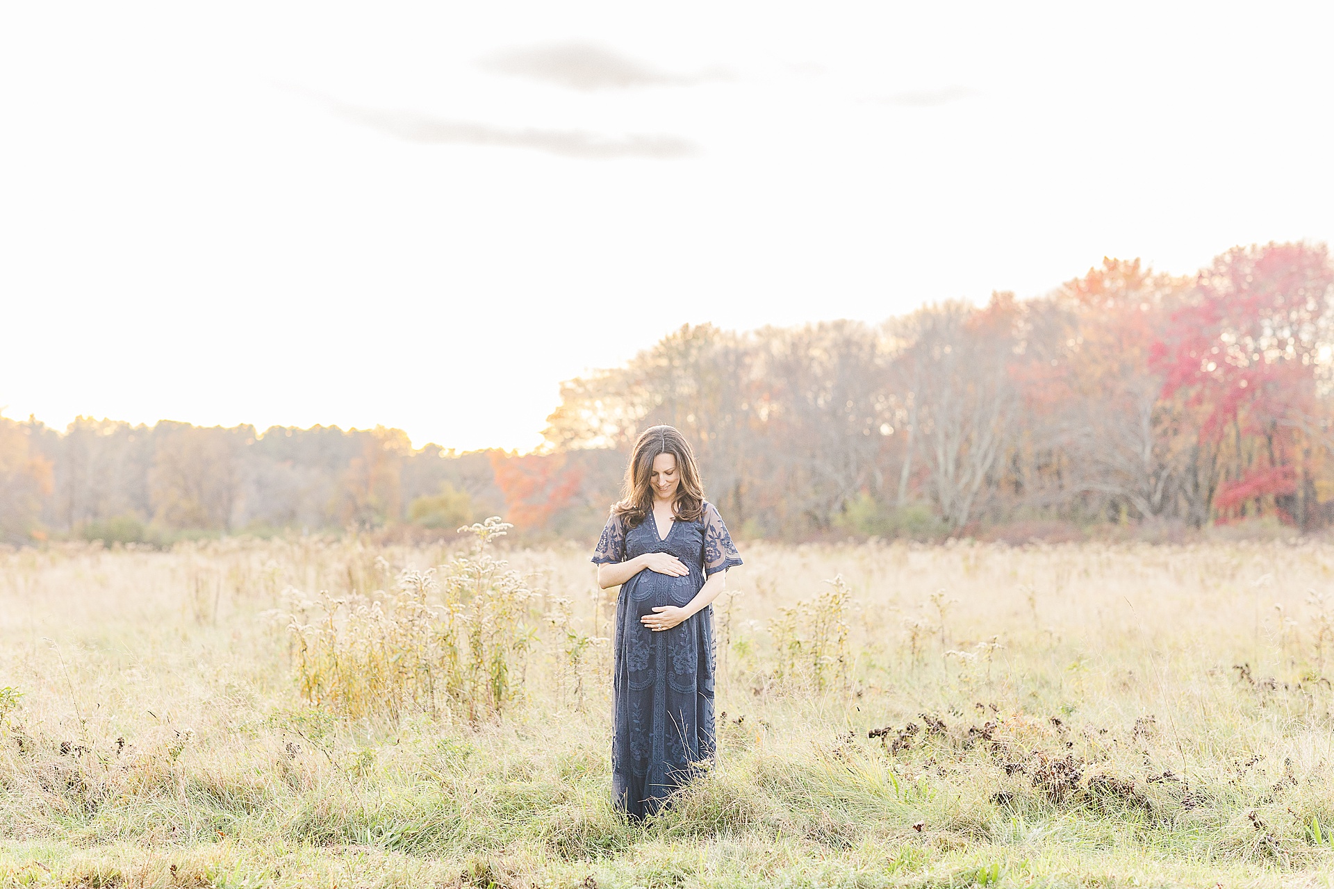 woman holds her pregnant belly during photo session with Sara Sniderman Photography at Cow Common, Wayland Massachusetts