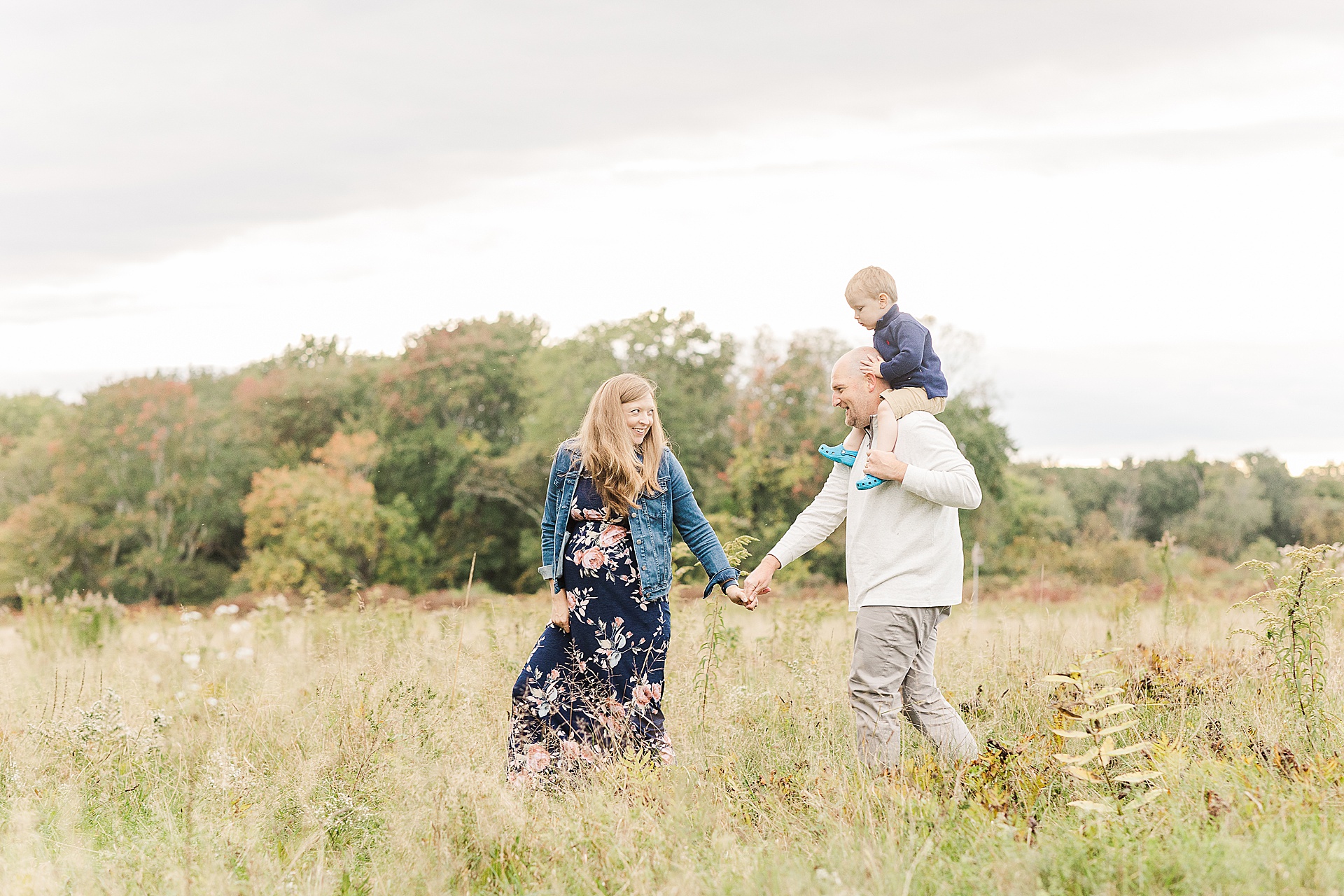family walks across the field during photo session with Sara Sniderman Photography at Cow Common, Wayland Massachusetts