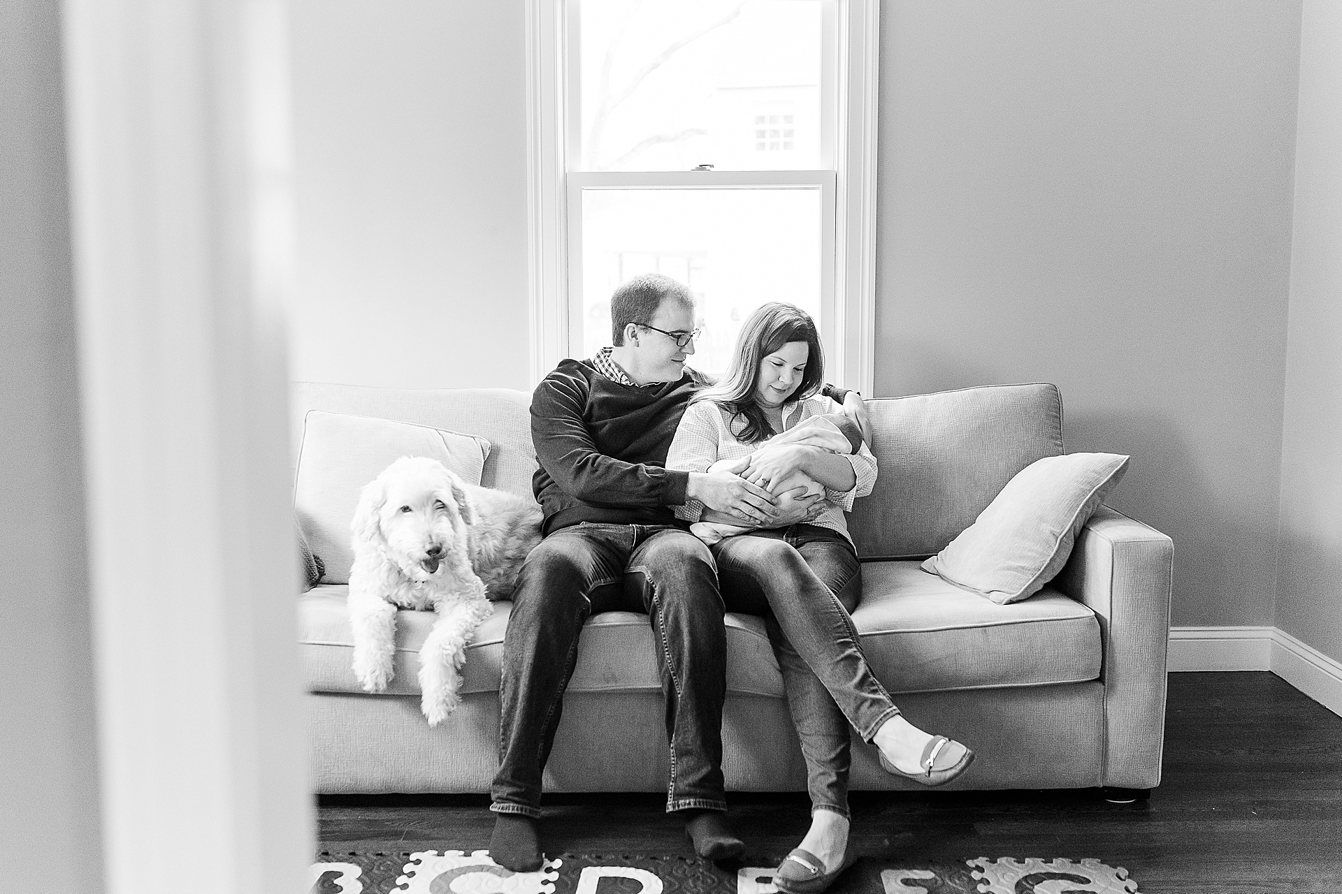 black and white of dog sitting on couch with family during in home newborn session with Sara Sniderman Photography in Natick Massachusetts