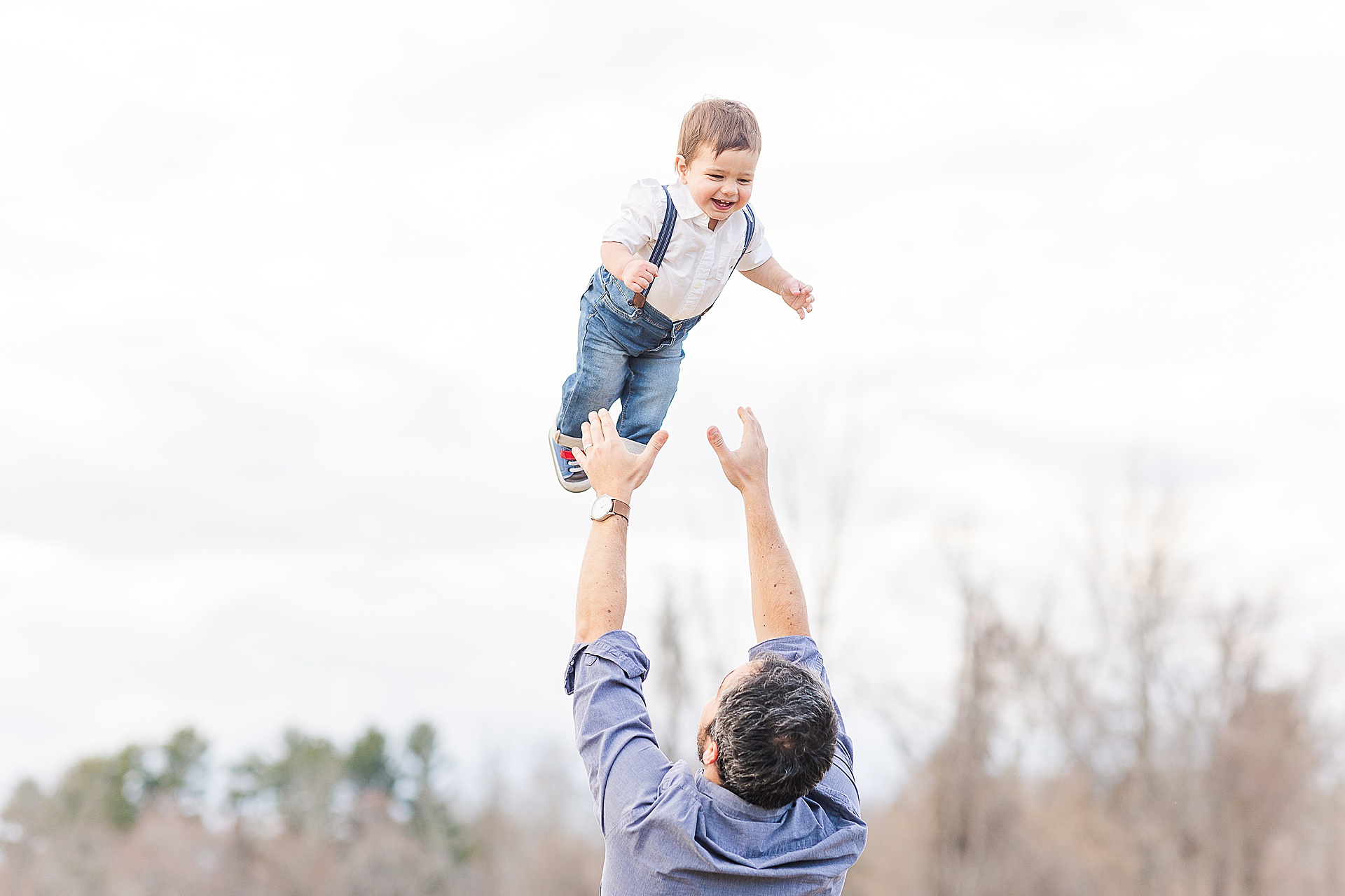dad throws son in air  during family maternity session in Natick Massachusetts with Sara Sniderman Photography
