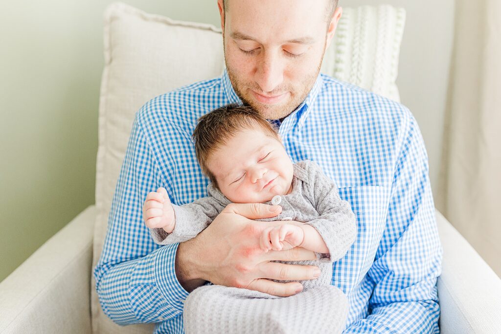 dad holds smiling baby during in home newborn photo session with Sara Sniderman Photography
