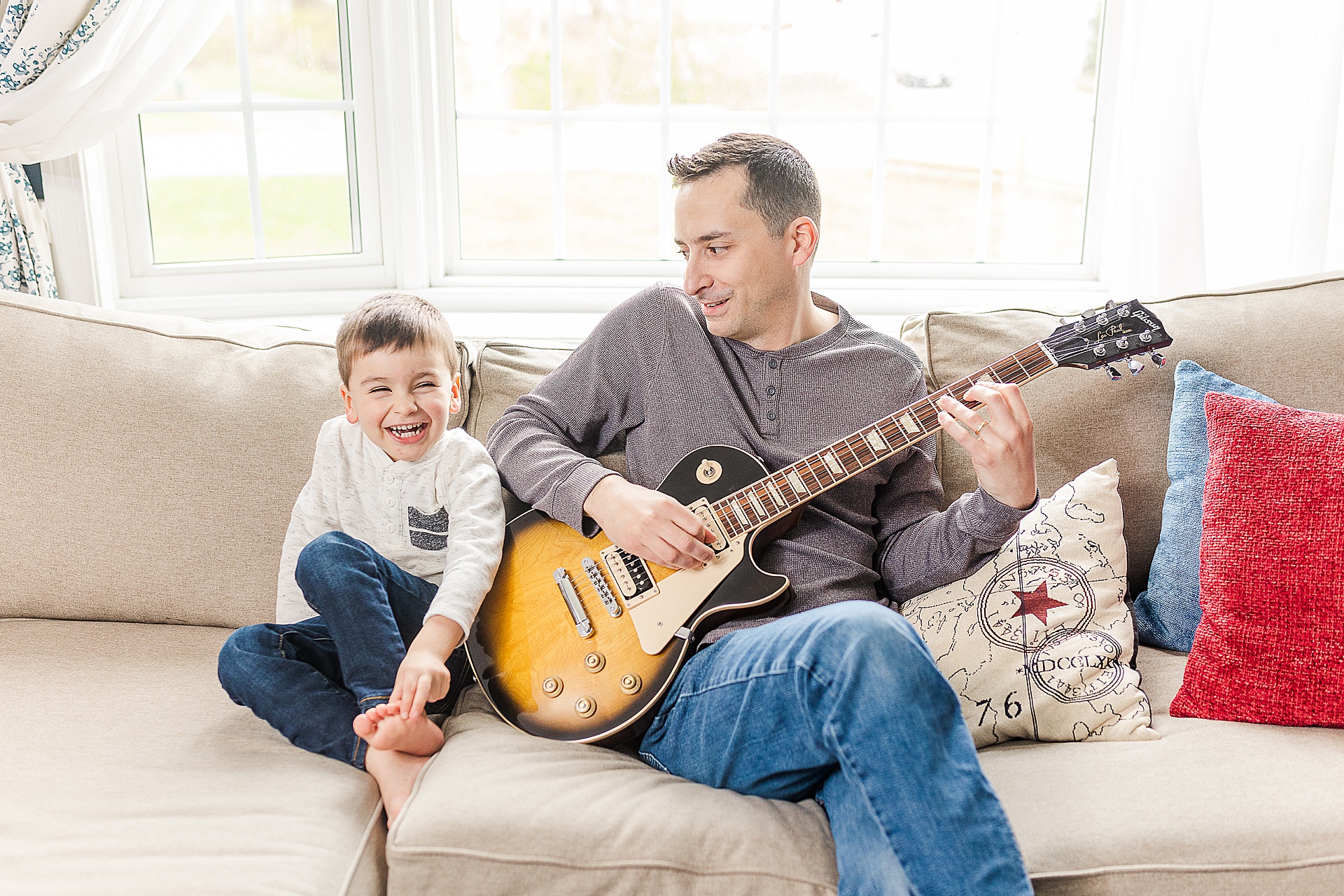 dad plays guitar with son in home photo session with one month old baby with Sara Sniderman Photography Natick Massachusetts