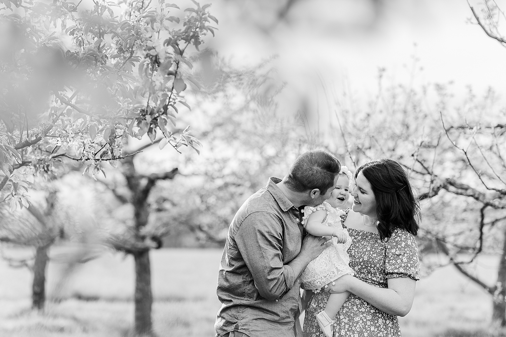 black and white of parent smiling at daughter in orchard during first birthday family photo session with Sara Sniderman Photography at Heard Farm in Wayland Massachusetts