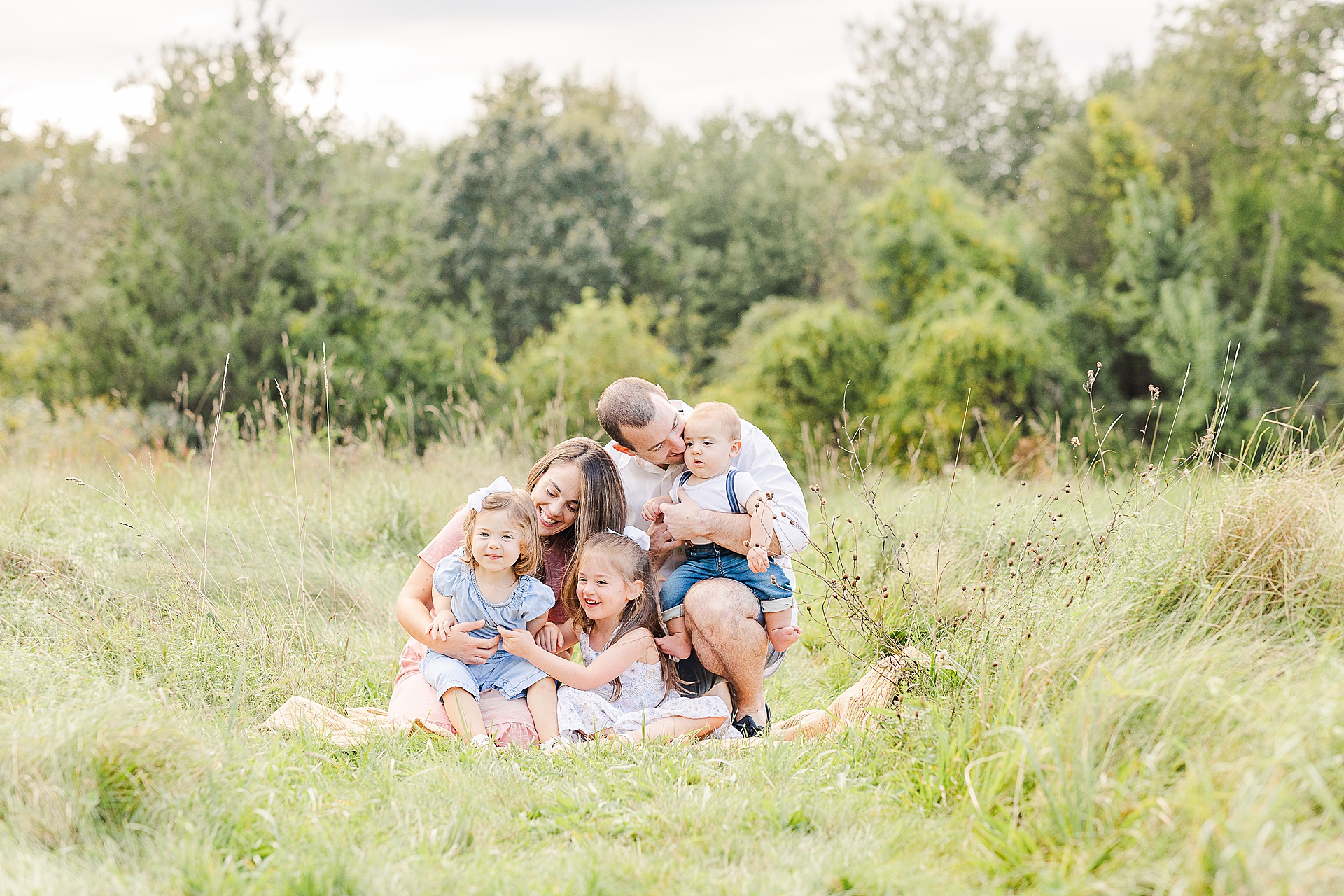 Family cuddles on a blanket during family photo session with Sara Sniderman Photography at Oak Grove Park in Millis Massachusetts