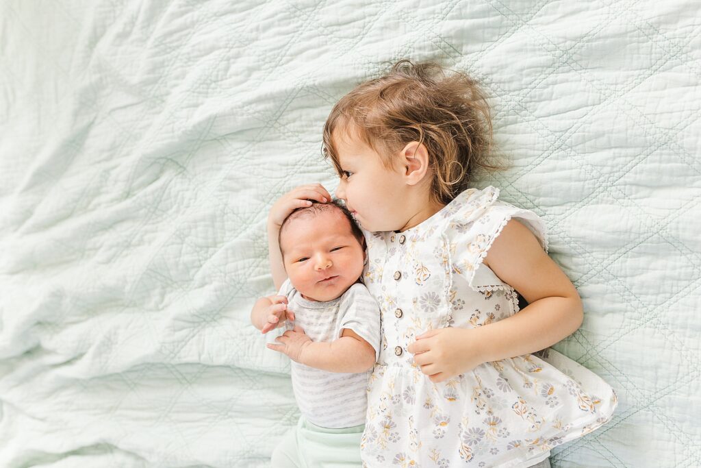 toddler kisses baby during in home photo session with Sara Sniderman Photography in Natick Massachusetts