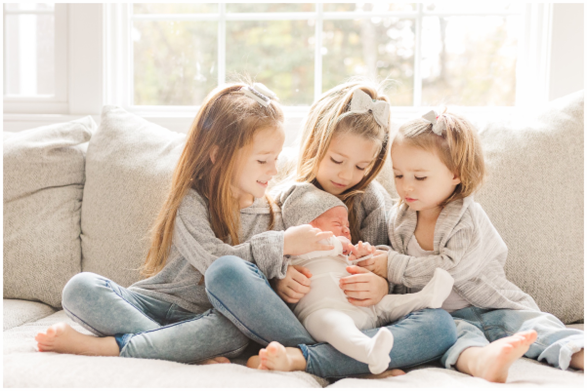 Three sisters hold baby brother during in home newborn photo session with Sara Sniderman Photography in Sherborn Massachusetts