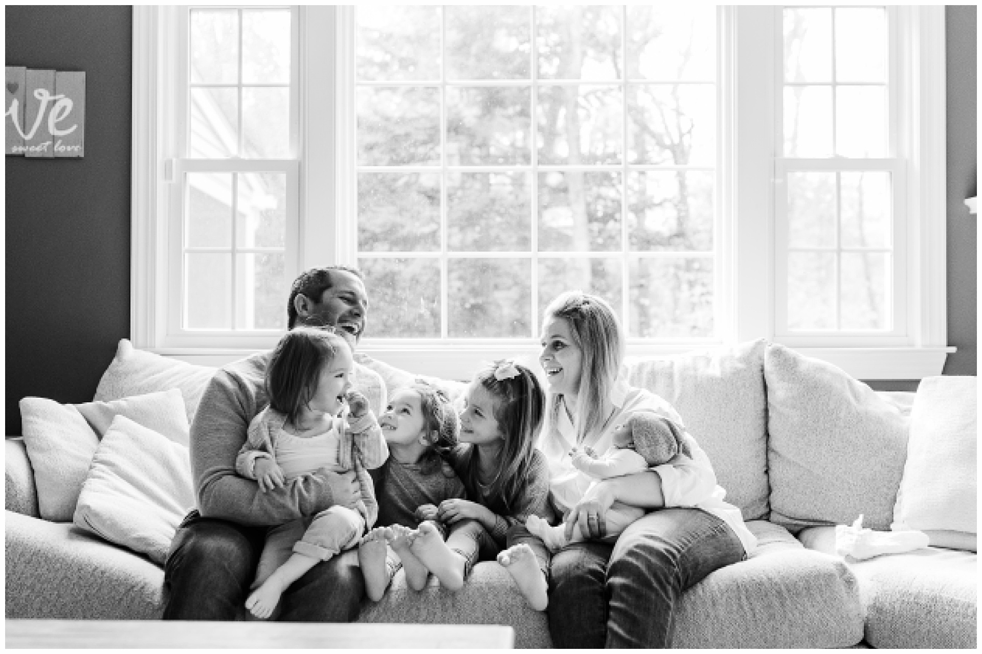 Black and white of family cuddling on couch during in home newborn photo session with Sara Sniderman Photography in Sherborn Massachusetts