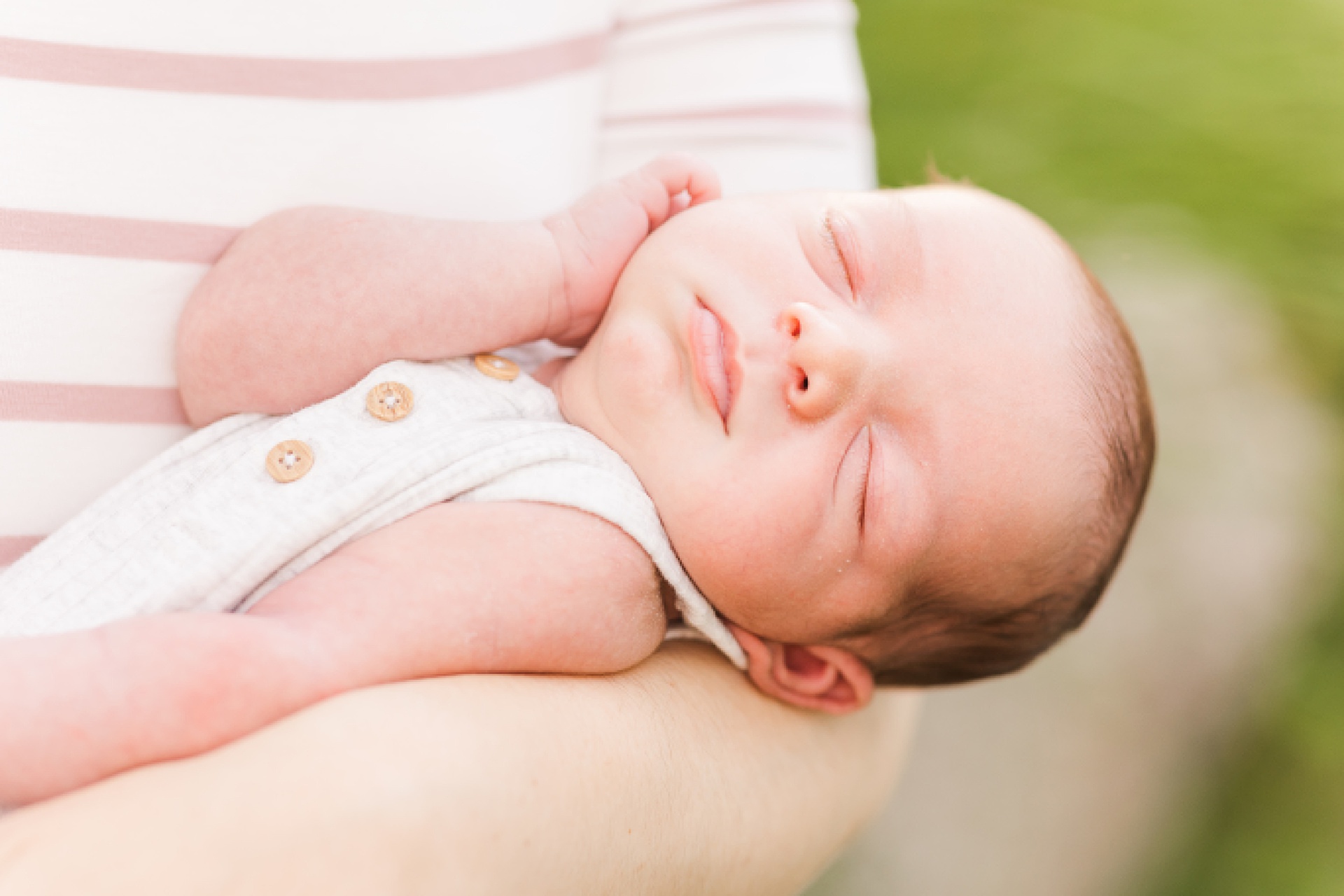 baby sleeps in mothers arms during outdoor newborn photo session with Sara Sniderman Photography at Oak Grove Park Millis Massachusetts