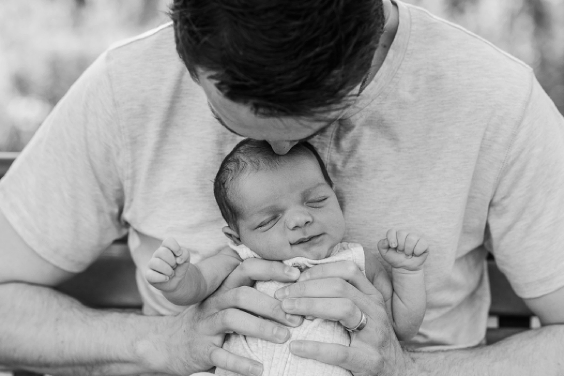 black and white of father kissing baby during outdoor newborn photo session with Sara Sniderman Photography at Oak Grove Park Millis Massachusetts