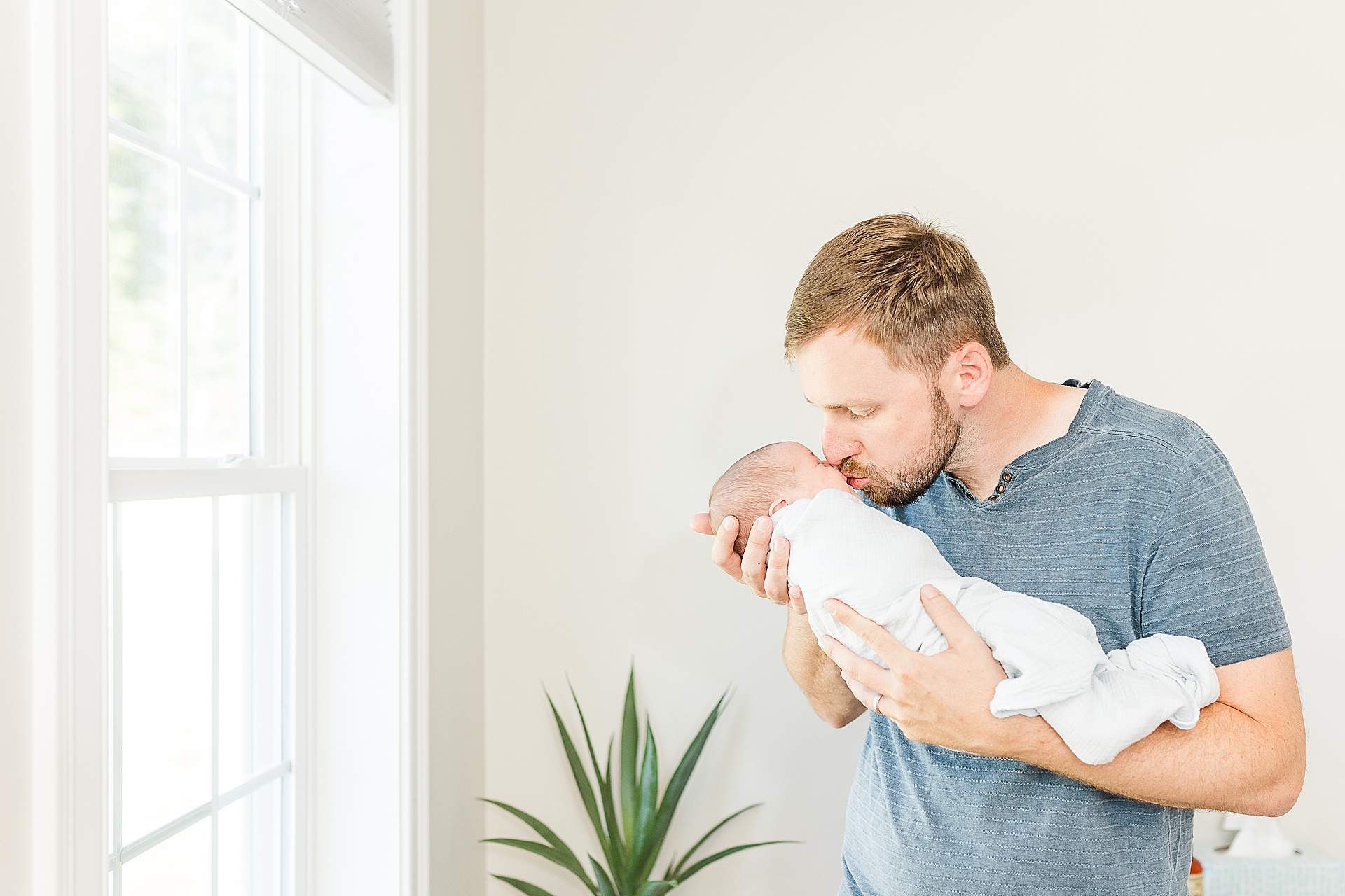 father kisses baby during in home newborn photo session with Sara Sniderman Photography Southborough Massachusetts