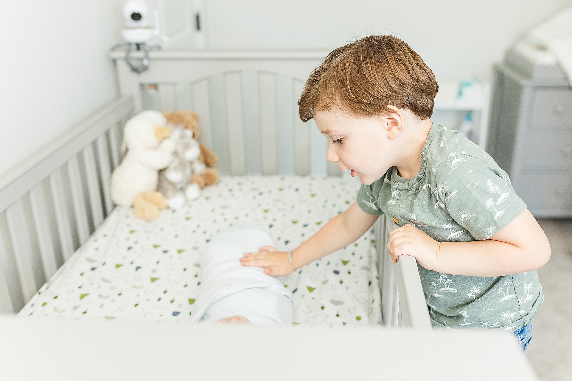 toddler looks into crib during in home newborn photo session with Sara Sniderman Photography Southborough Massachusetts