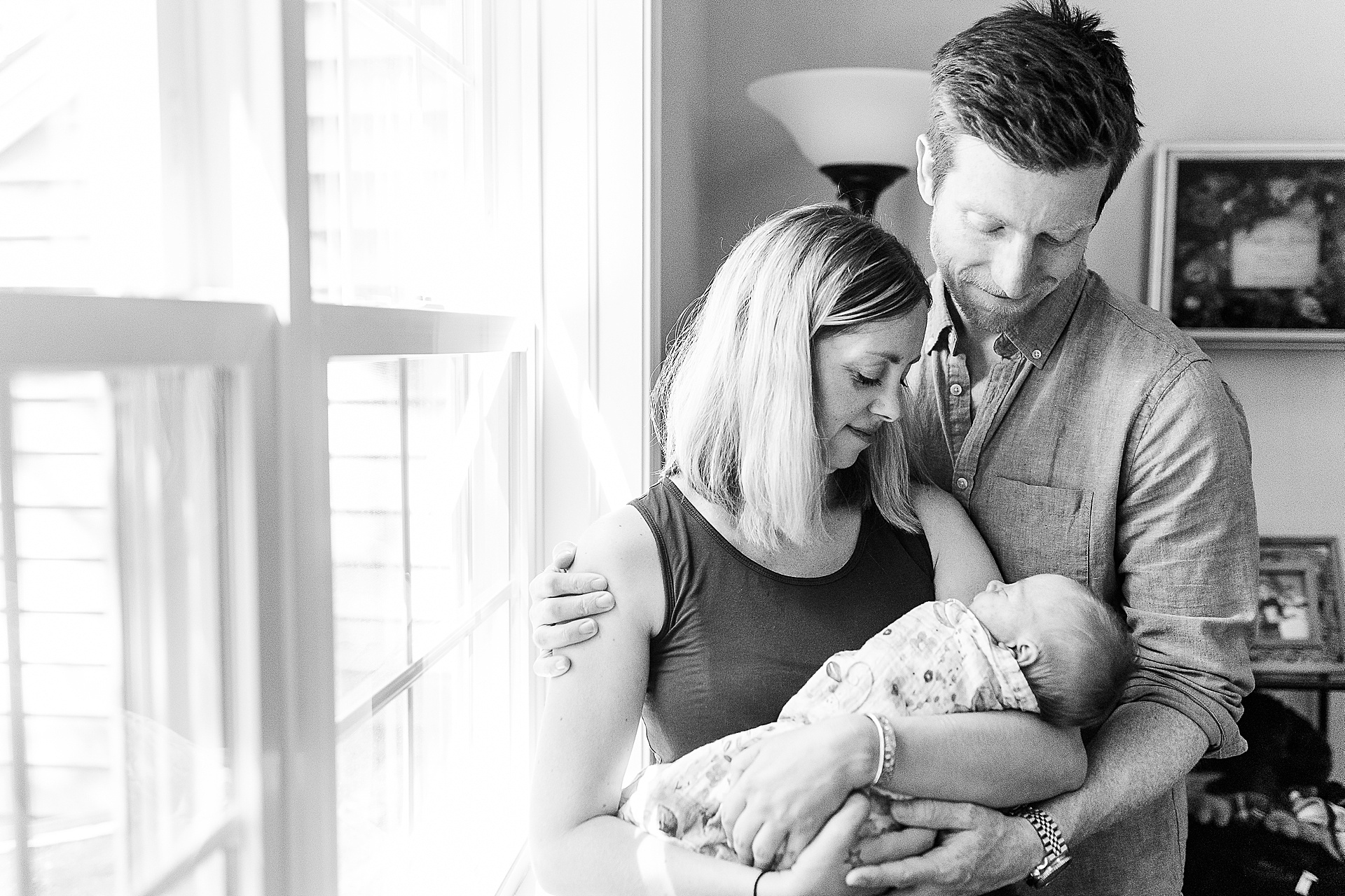 black and white of parents looking at baby during in home newborn photo session in Medway Massachusetts