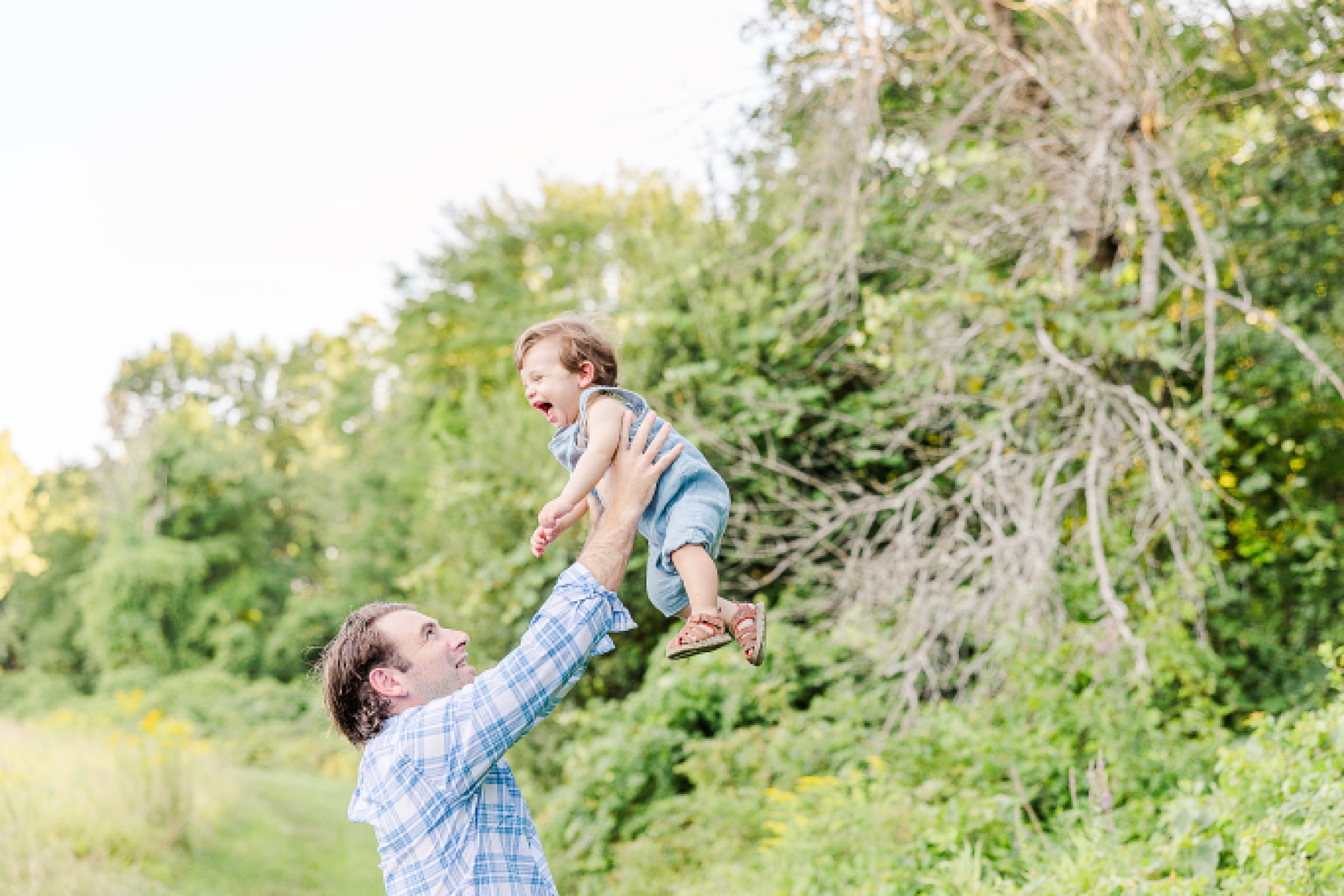 Dad holds son up high during one year old family photo session with Sara Sniderman Photography at Heard Farm in Wayland Massachusetts