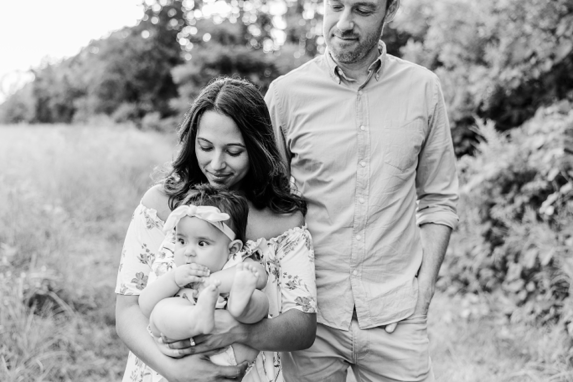 parents hold baby during family photo session with Sara Sniderman Photography at heard farm in Wayland Massachusetts.