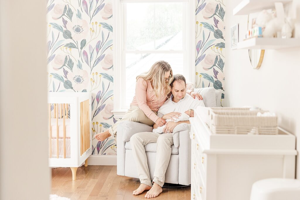 family snuggles in nursery with floral wall during in home newborn photo session with Sara Sniderman Photography in Natick Massachusetts