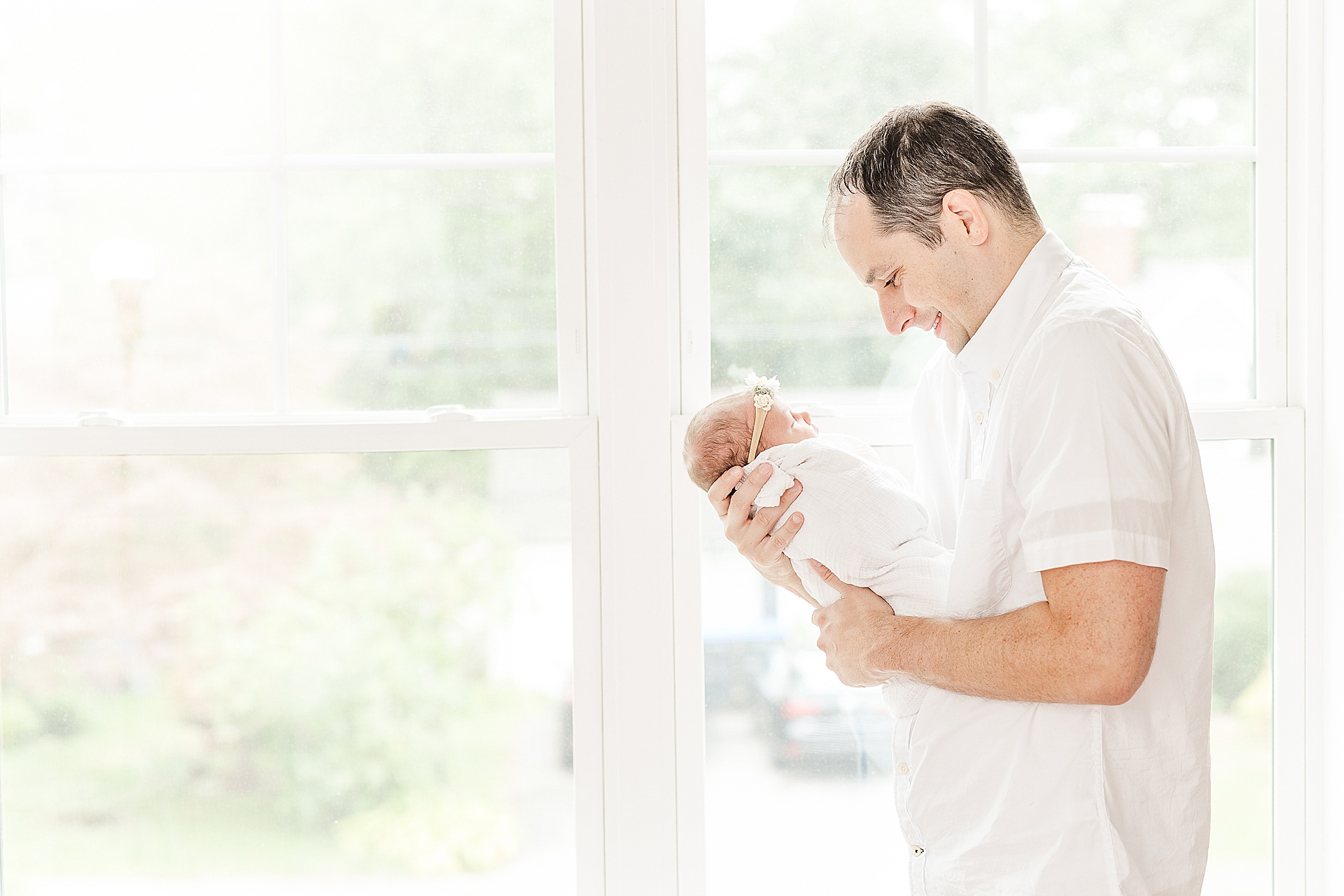 dad stands by window with baby during in home newborn photo session with Sara Sniderman Photography in Natick Massachusetts