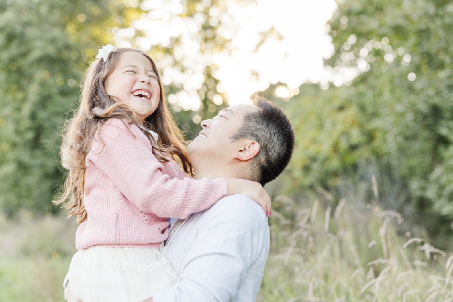 father holds daughter while she laughs during family photo session of the momming worker in Needham Massachusetts with Sara Sniderman Photography