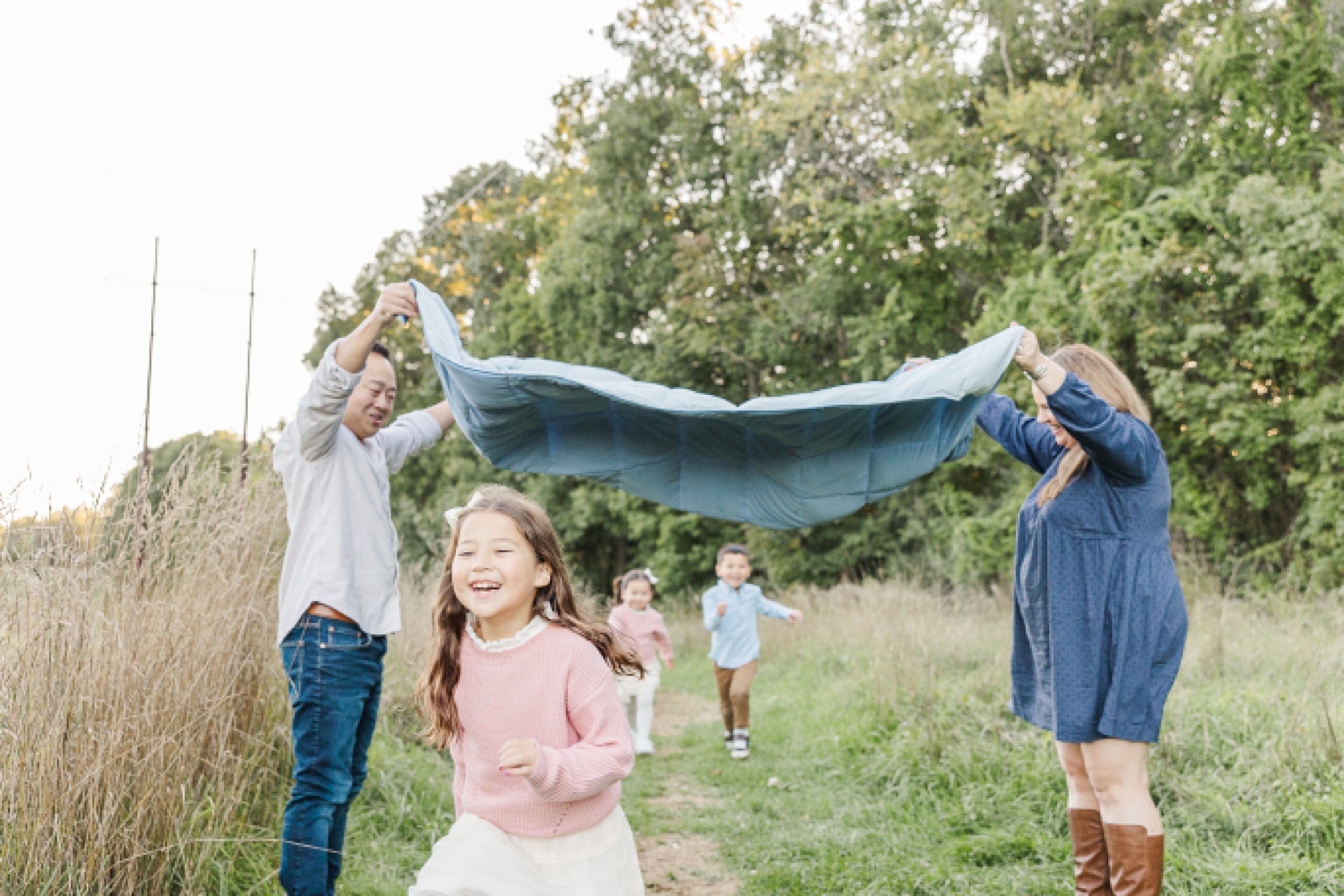 kids run under blanket during family photo session of the momming worker in Needham Massachusetts with Sara Sniderman Photography