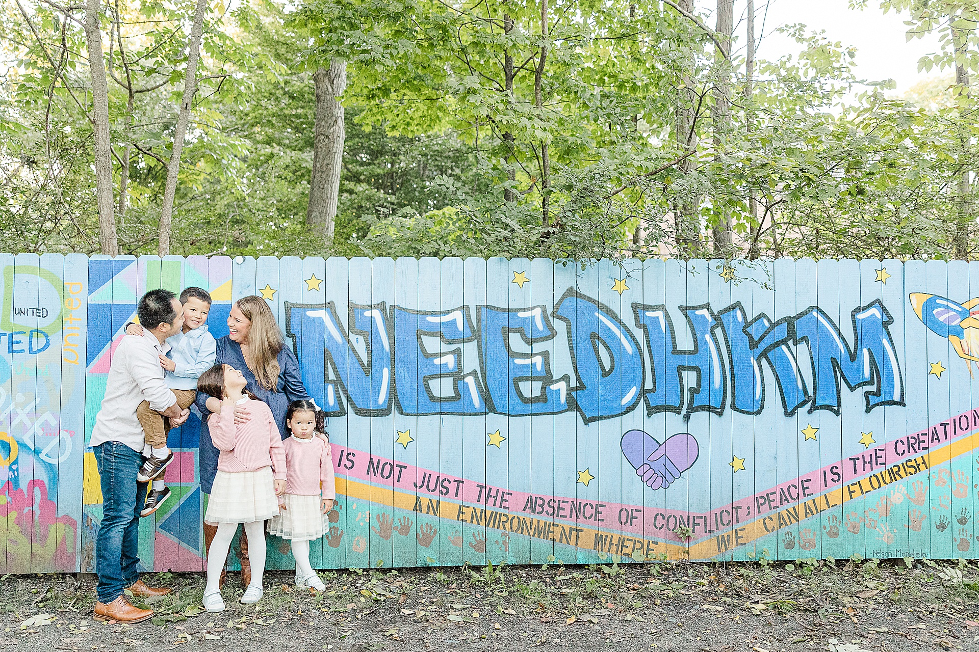 family stand next to Needham sign during family photo session of the momming worker in Needham Massachusetts with Sara Sniderman Photography