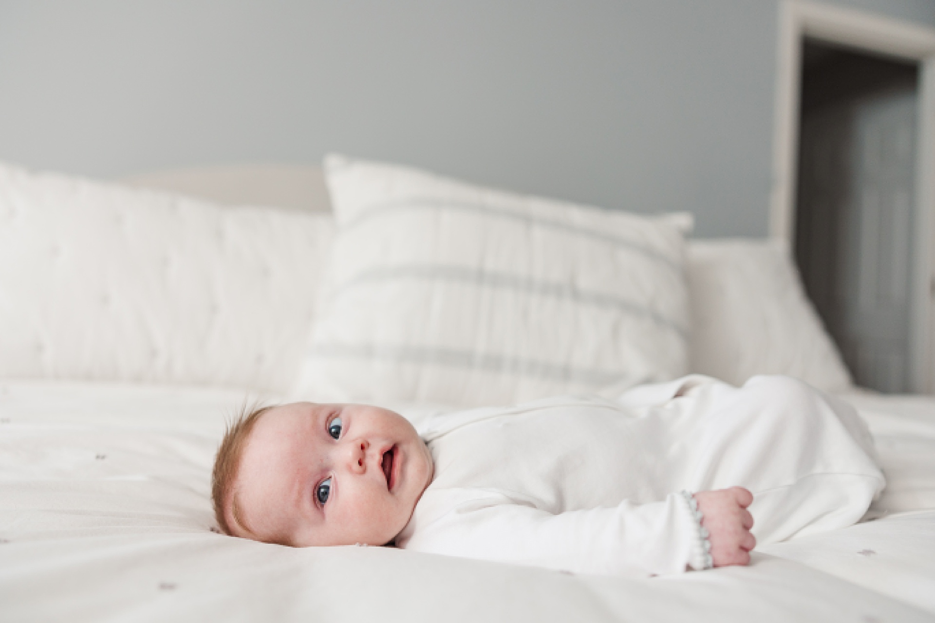 baby lays on bed during in home newborn photo session with Sara Sniderman Photography in Natick Massachusetts