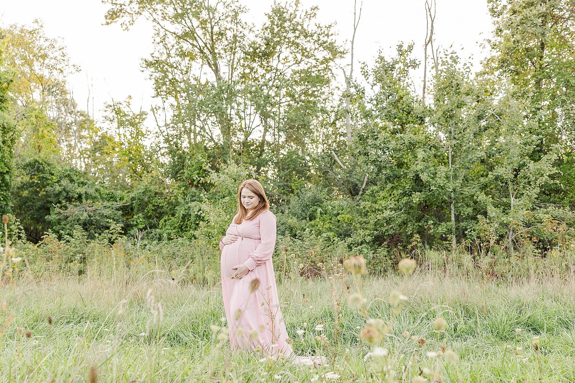 pregnant mom stands in field during maternity photo session with Sara Sniderman Photography at Medfield State Hospital
