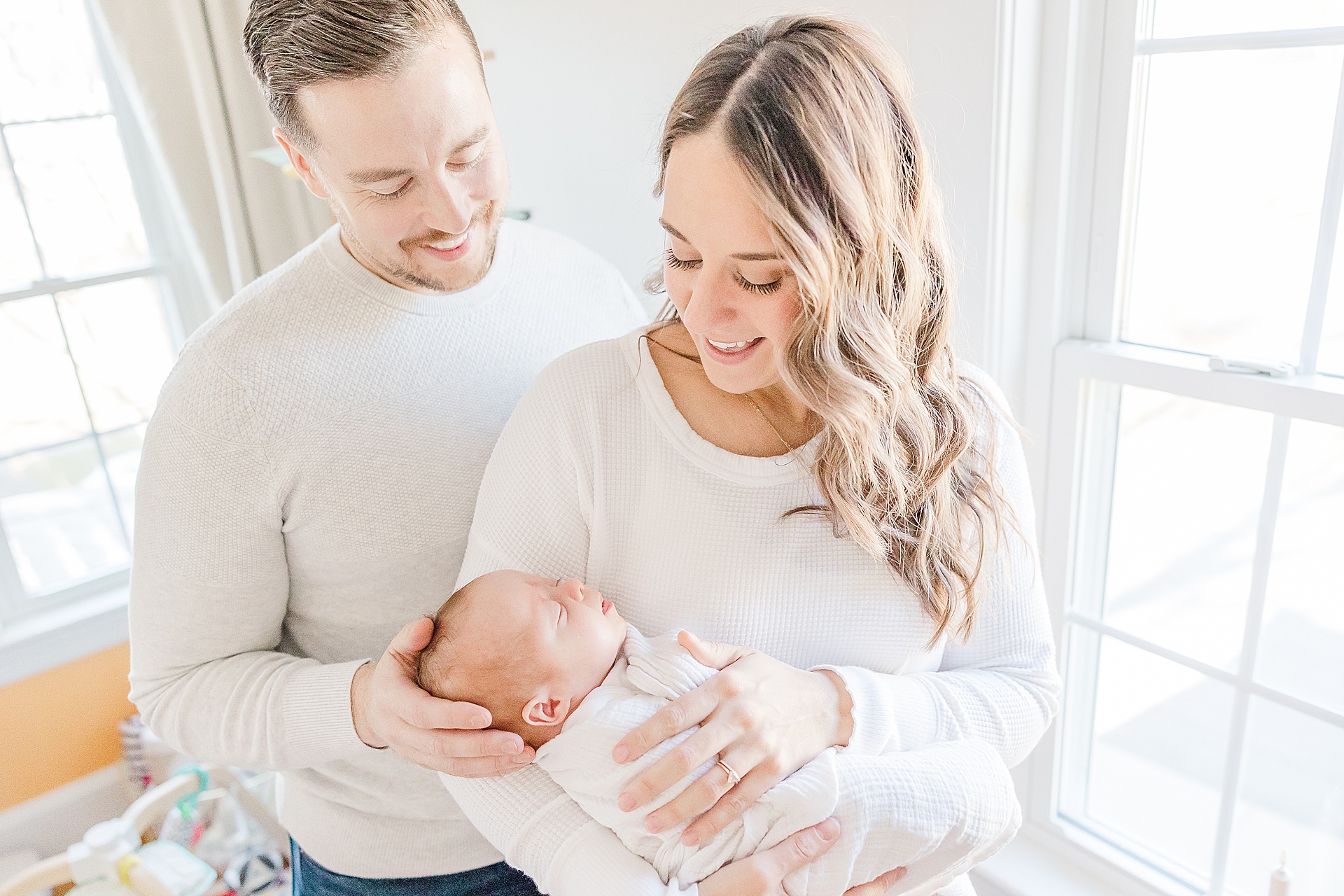 parents hold baby by window during in home newborn photo session for NICU baby in Natick Massachusetts