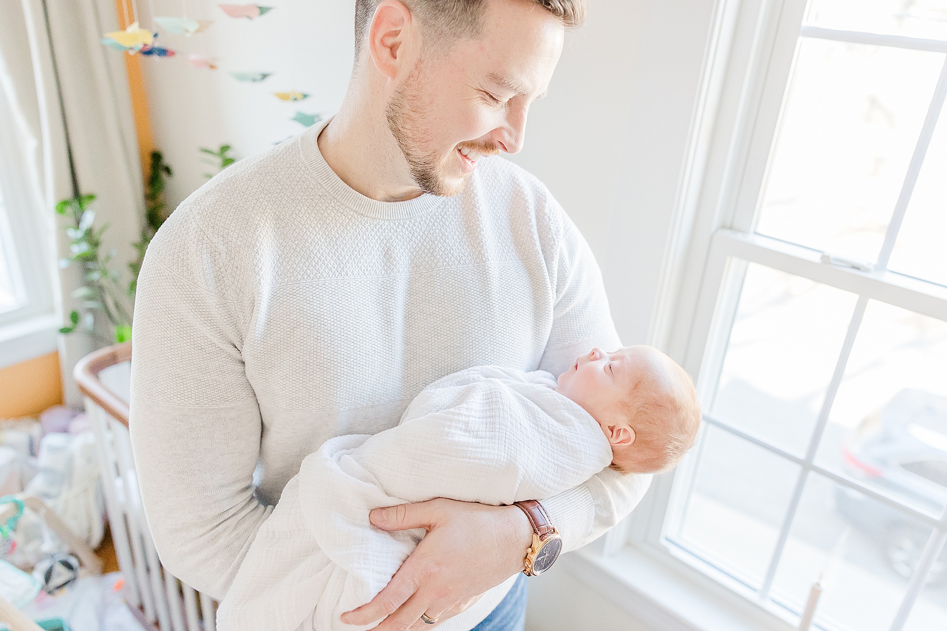 dad holds baby by window during in home newborn photo session for NICU baby in Natick Massachusetts