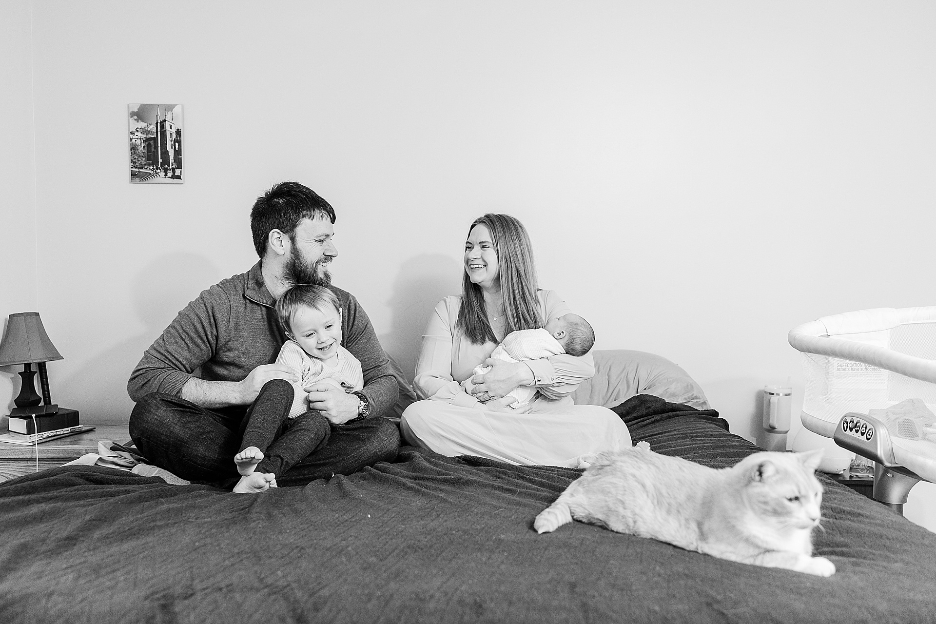 black and white of family on bed during in home newborn photo session with Sara Sniderman Photography in Wellesley Massachusetts