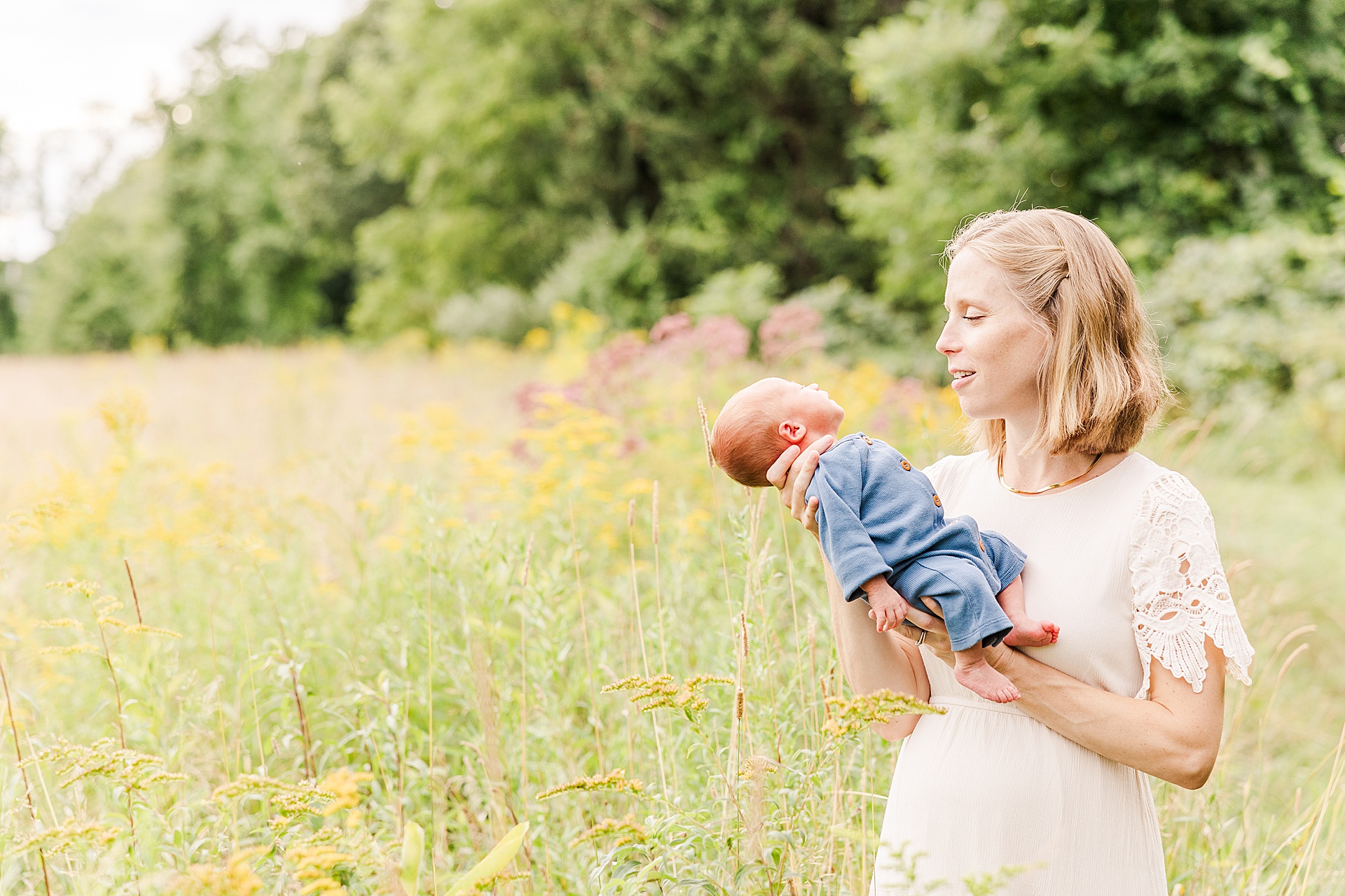 mom holds baby in field during outdoor newborn photo session at Heard Farm in Wayland Massachusetts with Sara Sniderman Photography