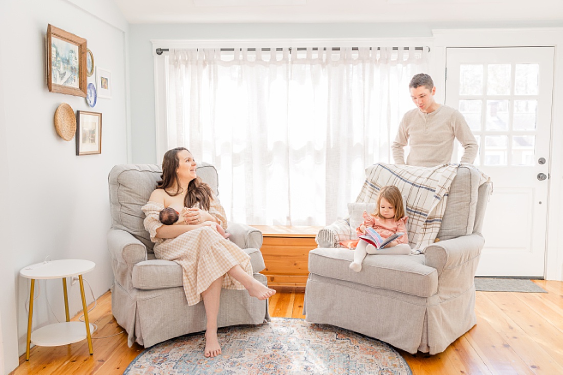 family sits in living room in home newborn photography metro west boston with Sara Sniderman Photography