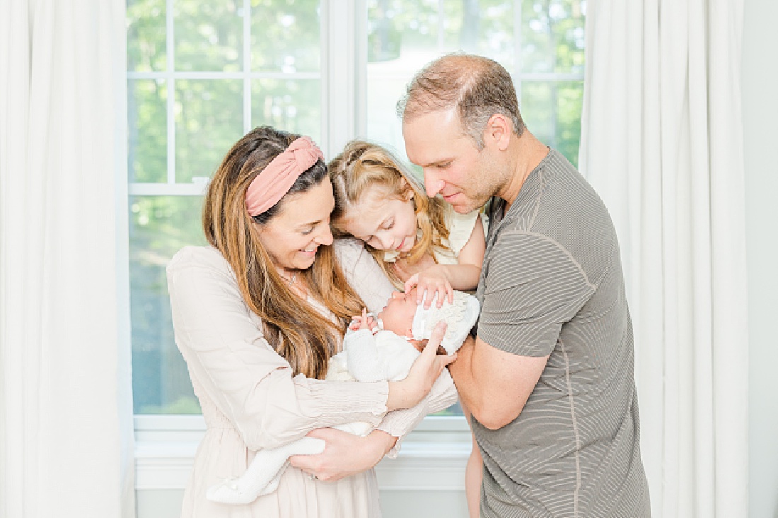 family cuddles newborn during baby bonnet newborn photo session in Natick Massachusetts with Sara Sniderman Photography 