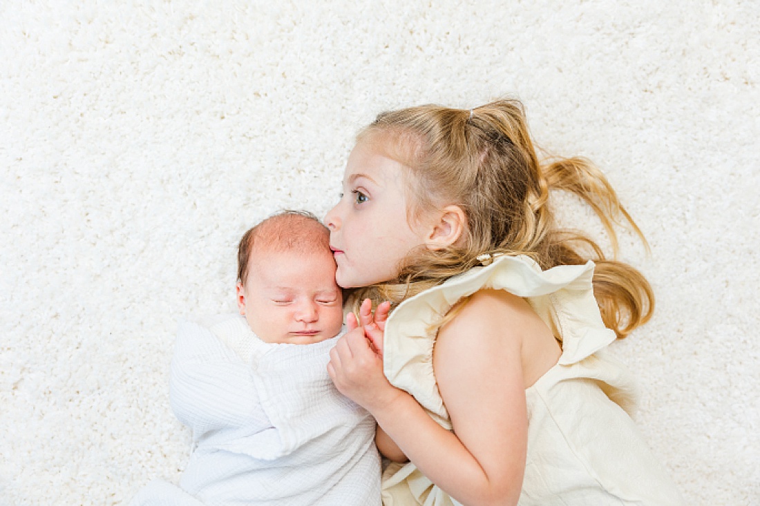 big sister kisses baby during baby bonnet newborn photo session in Natick Massachusetts with Sara Sniderman Photography 