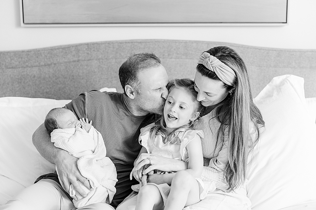 black and white of family sitting on bed during baby bonnet newborn photo session in Natick Massachusetts with Sara Sniderman Photography 