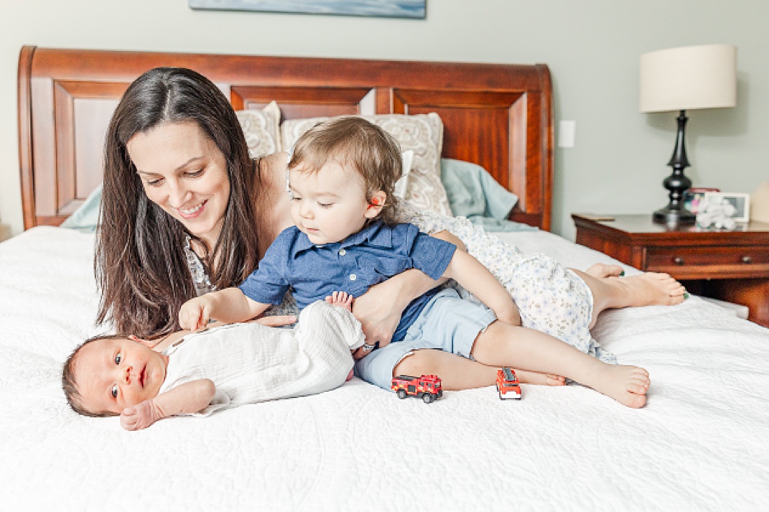 mom and middle son on bed with baby during In-home newborn photography in Metro West Boston with Sara Sniderman Photography