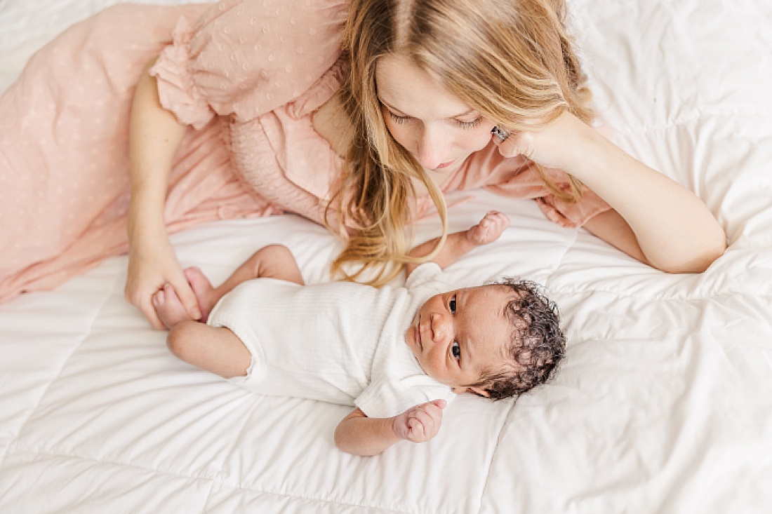 mom on bed with baby during lifestyle newborn photo session in metro west Boston with Sara Sniderman Photography