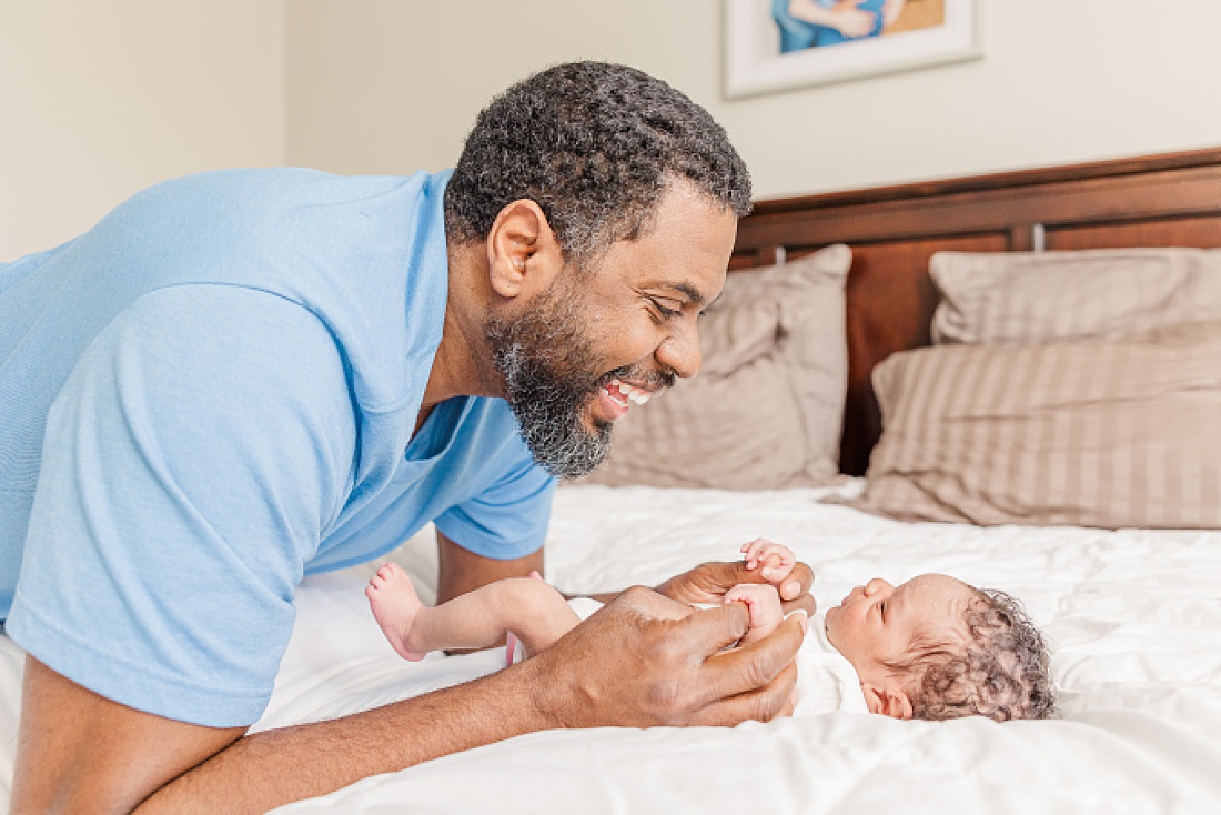 dad on bed with baby during lifestyle newborn photo session in metro west Boston with Sara Sniderman Photography