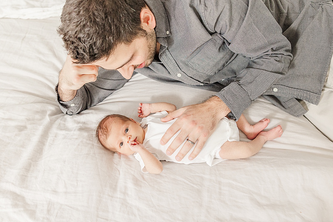 dad laying on bed during in-home newborn photo session in Natick Massachusetts with Sara Sniderman Photography