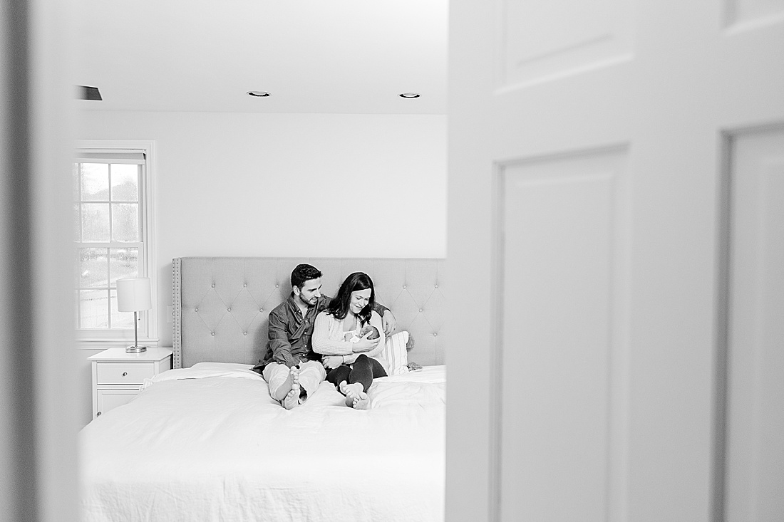 black and white of family on bed during in-home newborn photo session in Natick Massachusetts with Sara Sniderman Photography