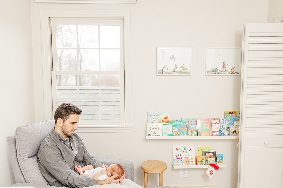 dad holding baby in nursery during in-home newborn photo session in Natick Massachusetts with Sara Sniderman Photography