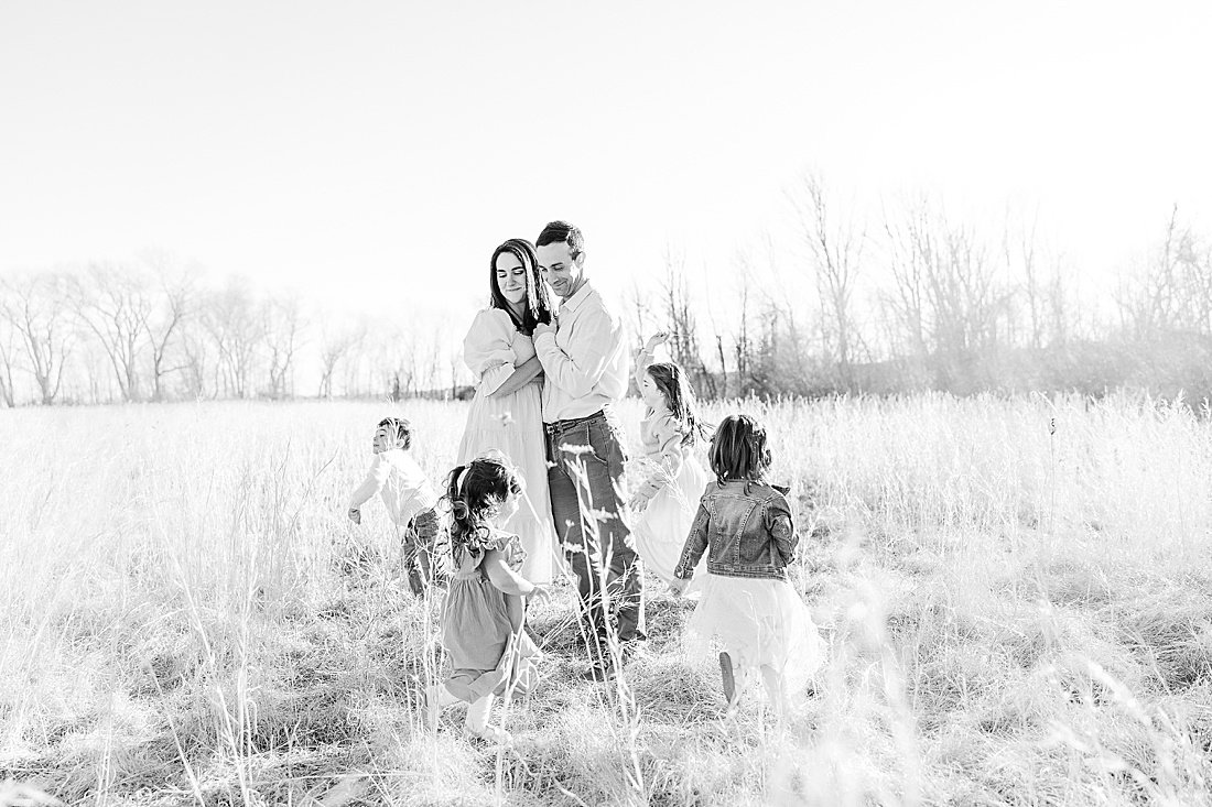 black and white of family running in grass during winter photo session in tall golden grass at medfield state hospital with Sara Sniderman Photography