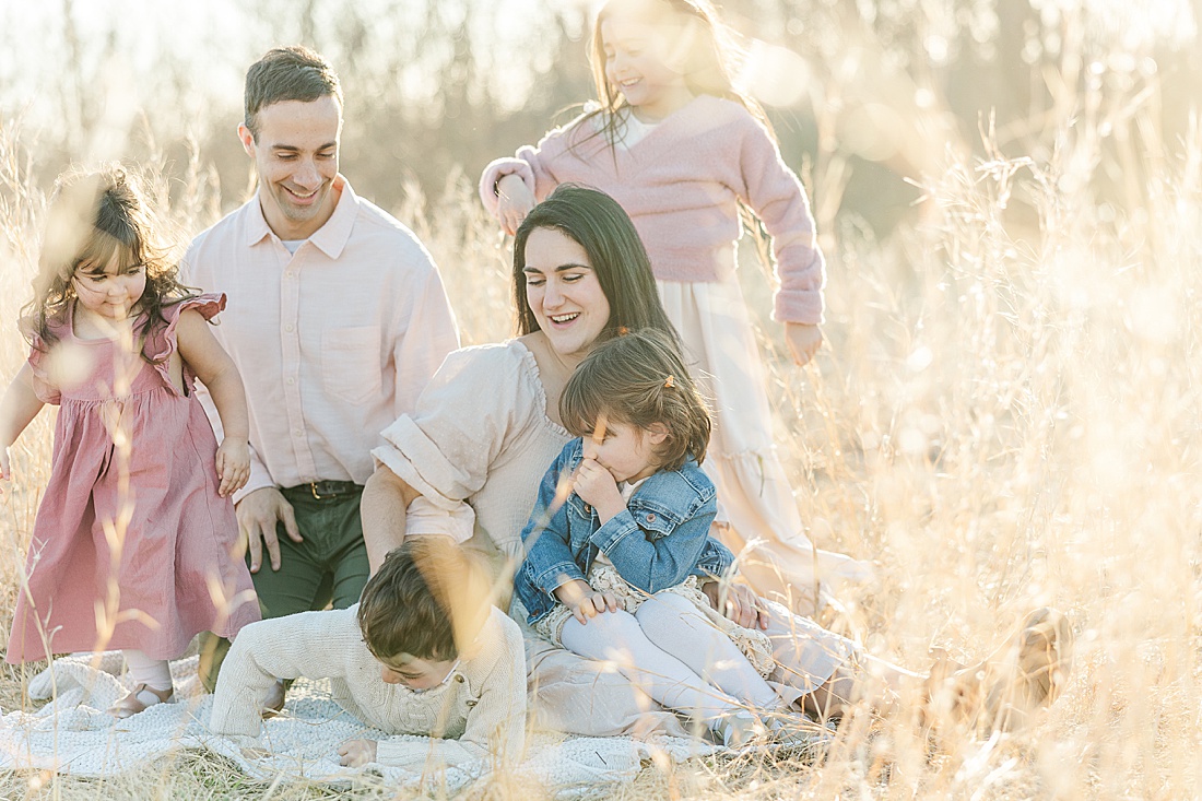 family cuddles on blanket during winter photo session in tall golden grass at medfield state hospital with Sara Sniderman Photography