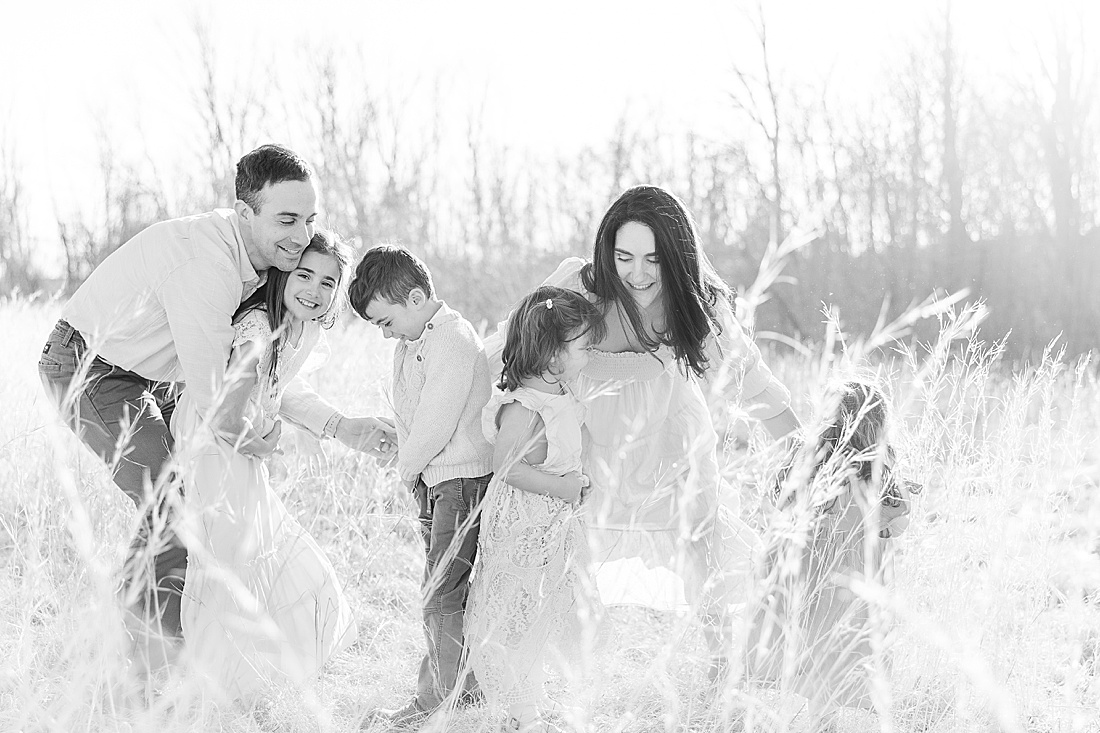 family laughts and embraces during winter photo session in tall golden grass at medfield state hospital with Sara Sniderman Photography