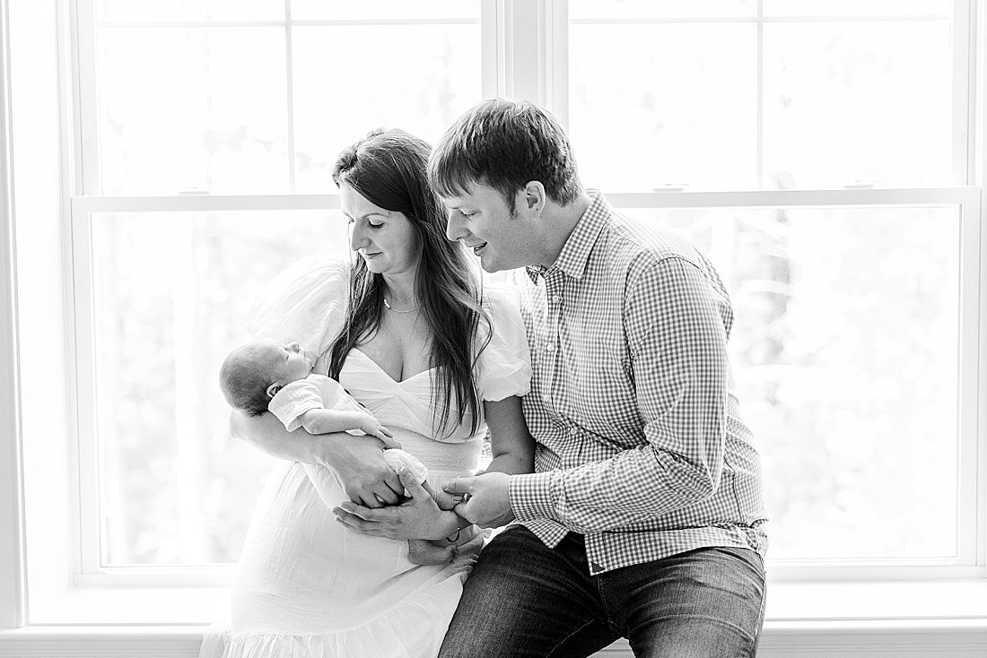 black and white photo of family by window during in-home photo session in Millis Massachusetts with Sara Sniderman Photography