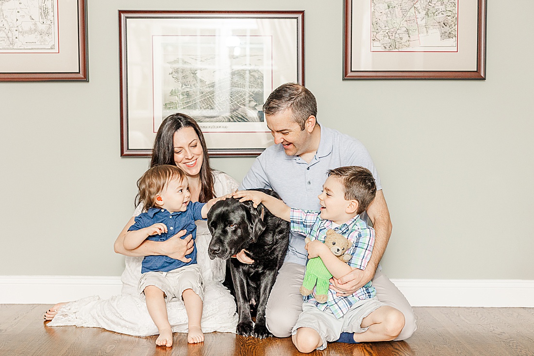 family sits with dog during in home family photo session with Sara Sniderman Photography in Metro West Boston