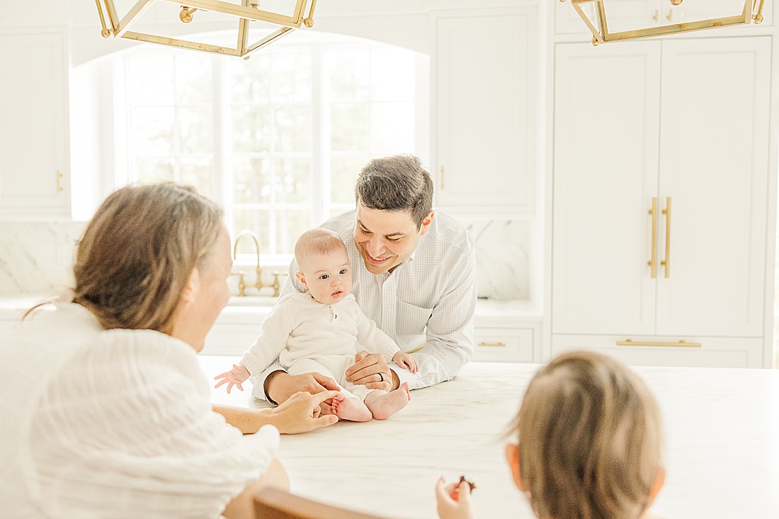 family sits in kitchen during in home family photo session with Sara Sniderman Photography in Metro West Boston