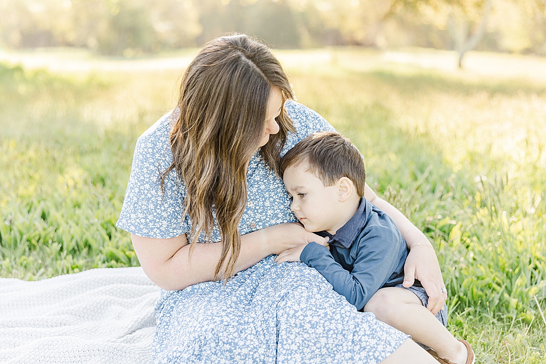 Mother cuddles with son during Spring Morning family photo session at Sprindale field in Dover Massachusetts with Sara Sniderman Photography. 