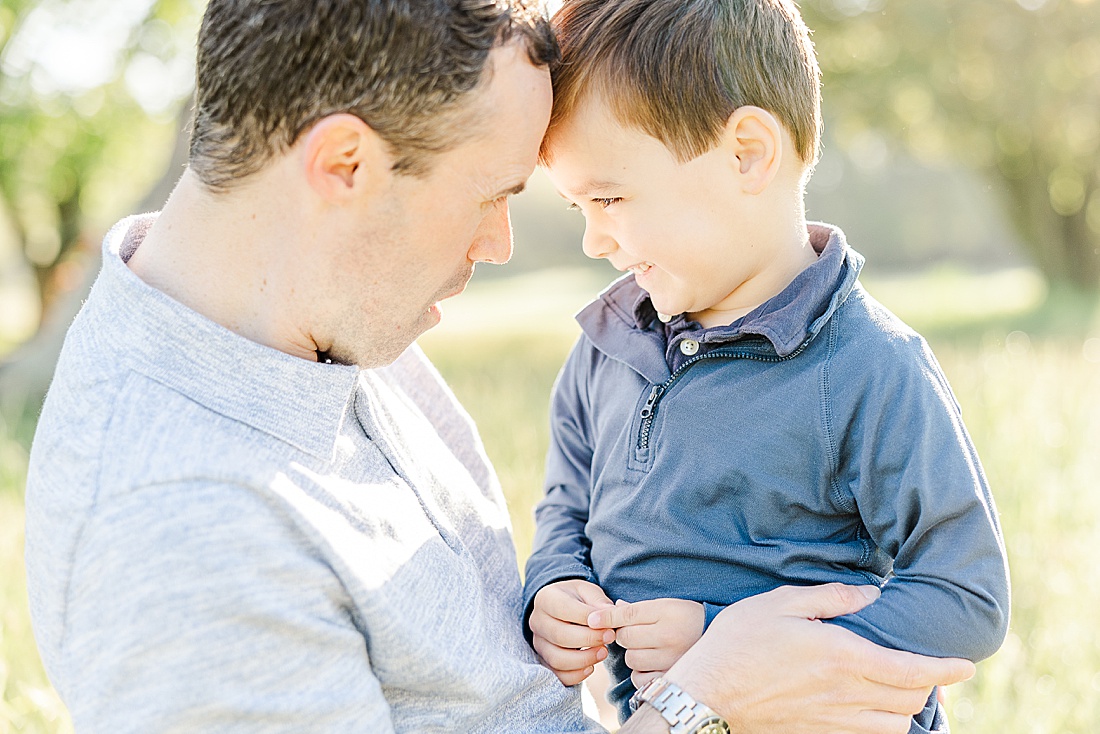 father and son look at each other during Spring Morning family photo session at Sprindale field in Dover Massachusetts with Sara Sniderman Photography. 