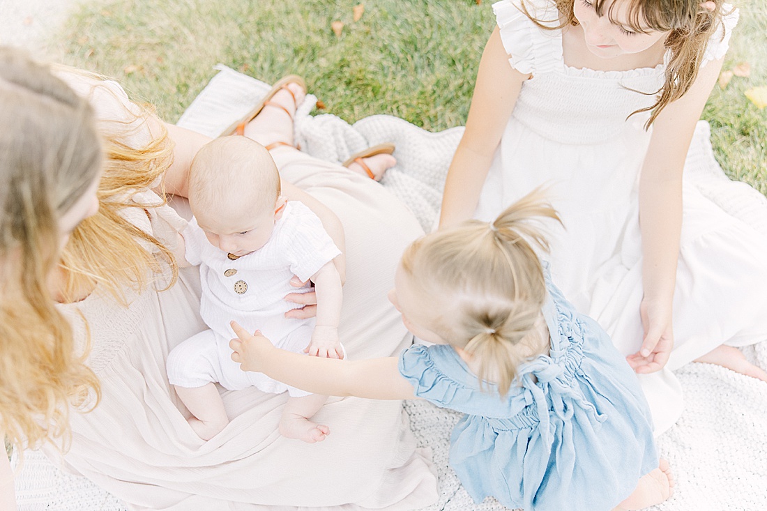 Image of professional family photo session taken by Sara Sniderman Photography, a family, newborn and maternity photographer serving the Metro West Boston area include: Natick, Needham, Newton, Wellesley, Wayland, Weston, Sherborn, Sudbury, Southborough, Medfield, Medway, Holliston, Framingham. The image is of sisters sitting on a blanket. 