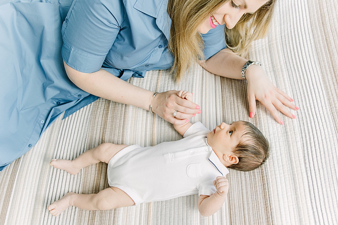 Image of professional maternity and newborn photo session taken by Sara Sniderman Photography, a family, newborn and maternity photographer serving the Metro West Boston area include: Natick, Needham, Newton, Wellesley, Wayland, Weston, Sherborn, Sudbury, Southborough, Medfield, Medway, Holliston, Framingham. The image is of mom laying on bed with baby