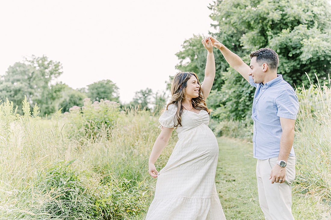 Image of professional maternity photos taken by Sara Sniderman Photography, a family, newborn and maternity photographer serving the Metro West Boston area include: Natick, Needham, Newton, Wellesley, Wayland, Weston, Sherborn, Sudbury, Southborough, Medfield, Medway, Holliston, Framingham. Image shows expectant couple dancing in a field. 